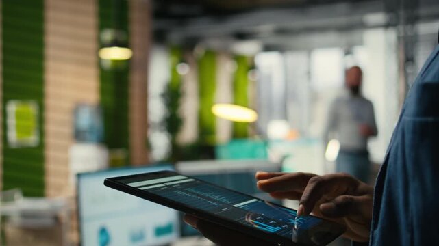Close up of man reviews performance metrics insights on tablet, driving business strategy and innovation while maintaining a workplace efficiency. Focusing on objectives and success. Camera A.