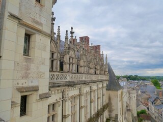 Façade et toits d'un château de style gothique surplombant une ville du Val de Loire.