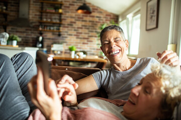 Happy senior lesbian couple relaxing on couch at home