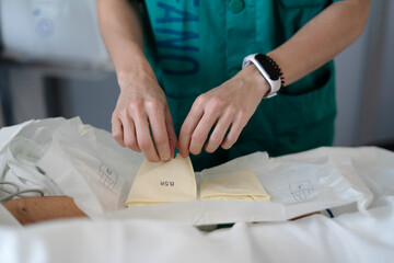 Nurse preparing sterile surgical gloves for operation in hospital room