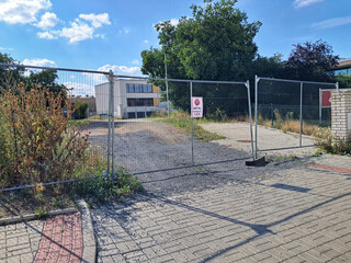 Partially open metal gate serves as an entrance to a property, with a building in the background...
