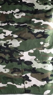 Textile featuring classic military camouflage pattern with green, brown, black, and white organic shapes forming an allover print design for apparel or gear.