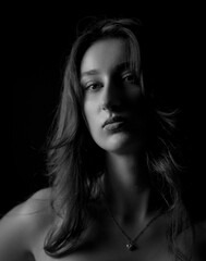 Studio portrait of beautiful young woman with long hair wearing a necklace on black background