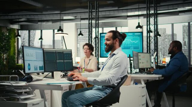 Office employee reviewing KPI metrics on monitor and analytics on files, building a vision and business strategy to accomplish objectives and success. Maintaining a professional mindset. Camera A.