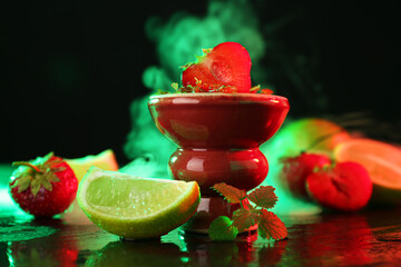 Hookah bowl with limes, strawberries, mint and smoke on black table, closeup