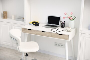 Desk with modern laptop, coffee and stationery in home office