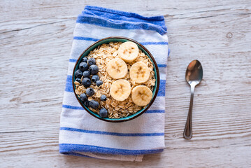 Top view of a porridge oatmeal with fresh fruit, a healthy breakfast bowl with oats, banana slices,...