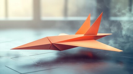 An orange origami paper airplane sits on a reflective surface, casting a shadow, with a blurred background.