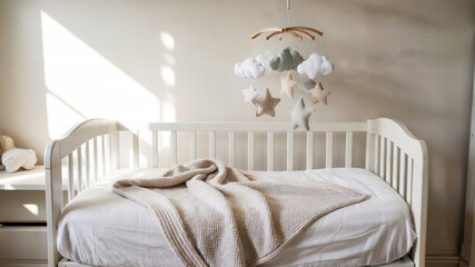 A small baby crib with toys and light bedding in a calm, well-designed nursery in Scandinavian style, concept of Baby Room Decoration