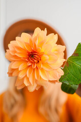 Woman faceless yellow sweater closing eyes with orange dahlia into camera Autumn Fall Bouquet for...