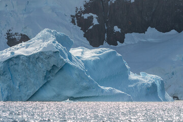 A tranquil Antarctic landscape, near Graham passage along Charlotte Bay, highlighting stark reflections, rugged mountains, and impressive icebergs.