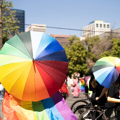 People holding rainbow umbrellas and pride flag at LGBTQ street parade