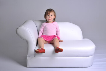 bebé menina fofa com roupa rosa em sofá, expressão engraçada 