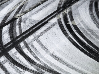 薄く雪が積もったアスファルトの道路にたくさんのタイヤの跡