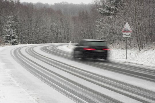 Car driving on snow-covered road, Warning sign, gradient, Hesse, Germany