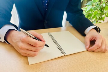 デスクで手帳に記入するビジネスマン