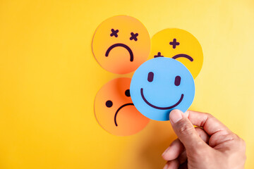 Choosing a happy smiley face for positive feedback, emotional rating, and satisfaction review, representing mood evaluation and mental health care concept in customer experience.