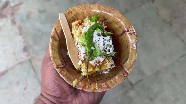 Kolkata style dhokla with chilly and shredded coconut served in paper plate.