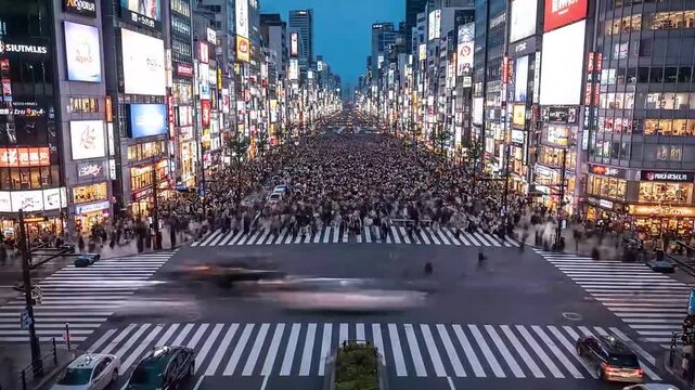 A remarkable pedestrian crossing of Tokyo, time lapse of busy Shibuya intersection at evening hour, view from high point. Car traffic pass by and street crosswalk filled with crowds of people