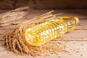 Vegetable oil extracted from rice seeds is packed in glass or plastic bottles with golden yellow rice seeds, which are an agricultural product, top view