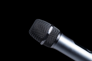Close-up of microphone in studio or concert performance on stage, on black background.