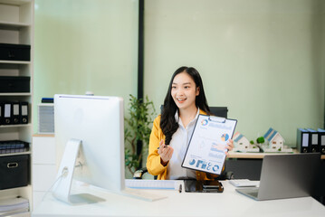 Asian businesswoman working with working notepad, tablet and laptop documents talking on the smartphone, tablet