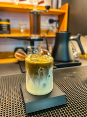 Matcha Latte served in a glass cup on a trendy coffee shop background.