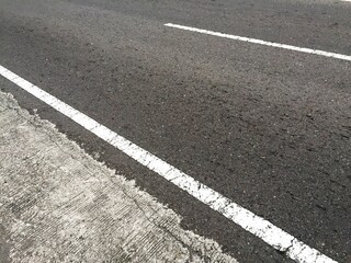 A straight, unbroken white line next to the edge of a paved road as a boundary between vehicles and pedestrian areas