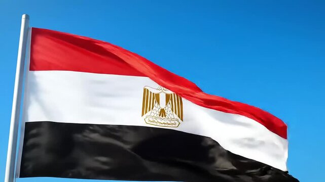 The national flag of Egypt, with red, white, and black stripes and the Eagle of Saladin, waves against a clear blue sky.