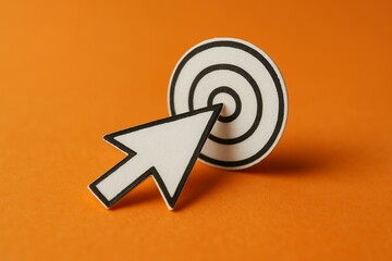 Craft paper cursor arrow hitting the center of target on bright orange background, concept for business strategy, marketing aim and success achieving