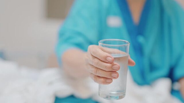 Senior woman with Tremor hand during taking glass of water in hospital. Parkinson disease April awareness month, Carpal Tunnel Syndrome, rheumatoid and brain injury and Neurological disorder concept