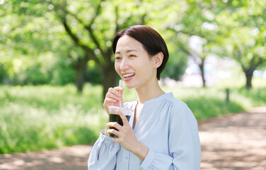 Fototapeta premium 屋外でアイスコーヒーを飲む40代女性