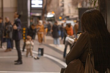 woman filming on the street with people around her