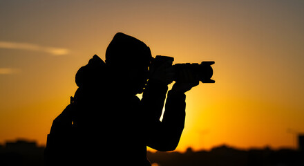 Silhouette of an Inspired Photographer Capturing the Golden Beauty of a Vibrant Sunset Sky with a Professional Camera