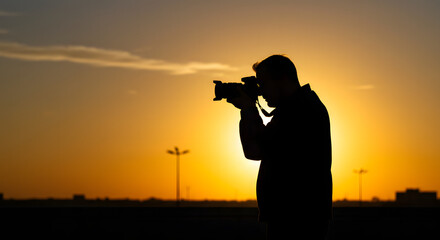 Silhouette of an Inspired Photographer Capturing the Golden Beauty of a Vibrant Sunset Sky with a Professional Camera