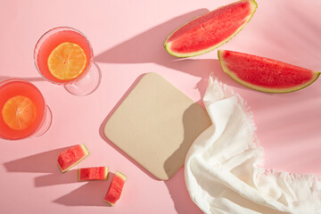 Pink summer flat lay with citrus fruits, watermelon slices, and refreshing drinks, leaving space for skincare or sunscreen product mockups.