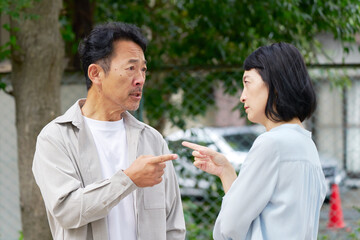 夫婦喧嘩する中年の夫婦　屋外