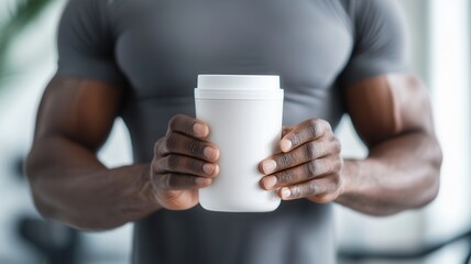 Muscular black athlete holding a protein shake, celebrating post workout recovery while emphasizing health and fitness in the gym