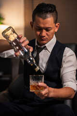 Businessman holding a glass of whiskey in a restaurant sitting on a sofa