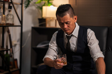 Businessman holding a glass of whiskey in a restaurant sitting on a sofa