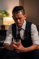Businessman holding a glass of whiskey in a restaurant sitting on a sofa	
