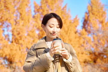屋外でコーヒーを飲む女性　ミドルエイジ　紅葉
