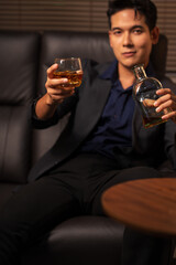 Businessman holding a glass of whiskey in a restaurant sitting on a sofa