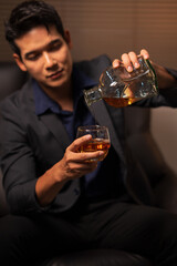 Businessman holding a glass of whiskey in a restaurant sitting on a sofa