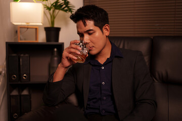 Businessman holding a glass of whiskey in a restaurant sitting on a sofa