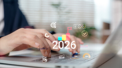 Business hand typing on laptop with futuristic data analytics dashboard and 2026 goal icons....