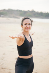 Yoga instructor performing warrior two pose on sandy beach