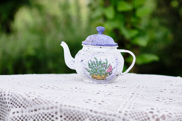 Charming vintage teapot displayed on a lace tablecloth in a lush garden setting during the afternoon