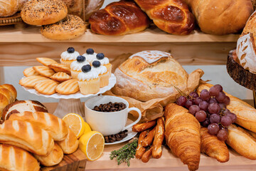 Variety of baked goods including croissants, bread, cupcakes with coffee grapes on display in bakery.