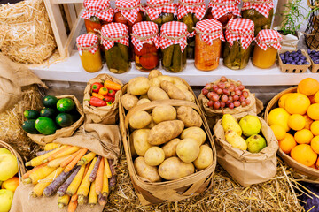Fruits vegetables arranged with jars of pickled items at vibrant farmers market in fall.
